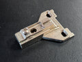 A small metal hardware component with a silver-toned finish, photographed on a dark textured surface.
